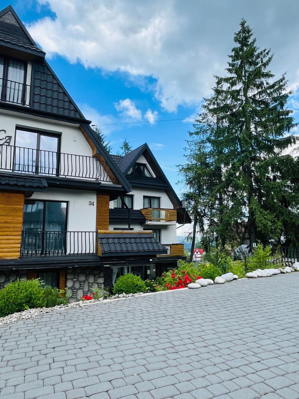 Pokoje Baca — góralska architektura budynku wśród świerków